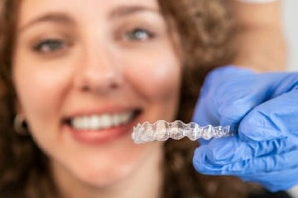 Orthodontic specialist adjusting and placing invisible aligners on a caucasian woman. Concept of invisible orthodontic technique.